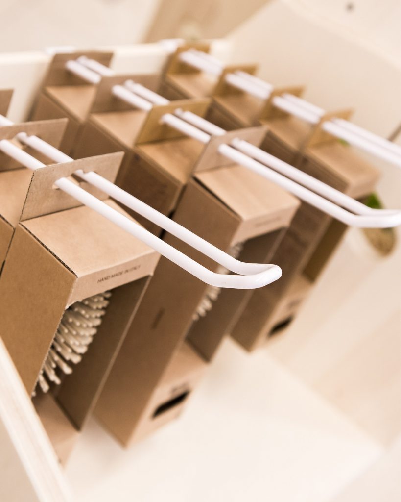 Gros plan sur une broche double utilisée pour suspendre des boîtes de brosses en carton recyclé.