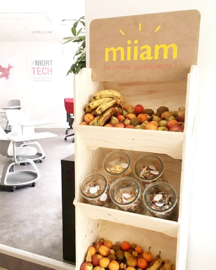 Présentoir en bois modulable exposant des fruits frais et snacks sains, conçu par IZZIBOX.